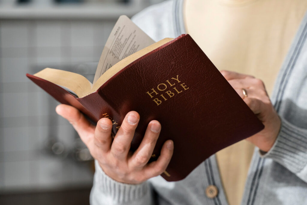 Eine Person hält eine geöffnete Bibel mit Ledereinband in der Hand. Der Titel „Holy Bible“ ist gut lesbar.